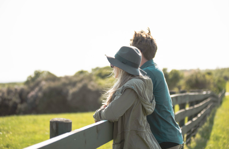 A couple lean on a fence and admire the view