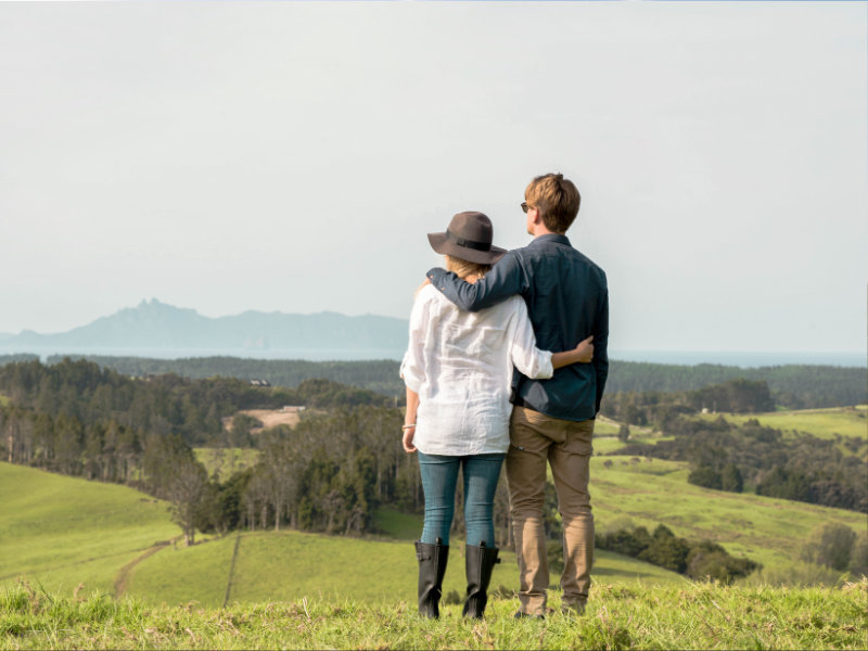 a couple stands and admires the view of the estate and the island in the distance 